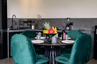 a kitchen with a table with green chairs at Rice field View with Sauna Projector and Jacuzzi Unique design in Canggu