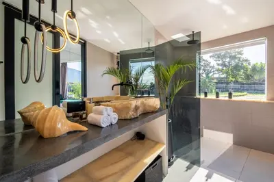 a bathroom with a sink and a large mirror at Rice field View with Sauna Projector and Jacuzzi Unique design in Canggu