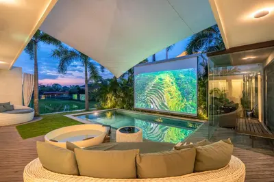 a living room with a large tv and a pool at Rice field View with Sauna Projector and Jacuzzi Unique design in Canggu