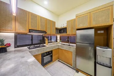 a kitchen with wooden cabinets and stainless steel appliances at Kalya Villa by RPM in Seminyak