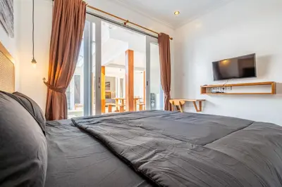a bedroom with a large bed with a television on the wall at Lumturi House - Centrally Located in Seminyak