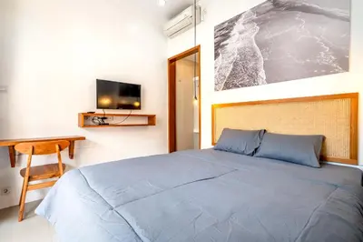 a bedroom with a bed and a desk and a tv at Lumturi House - Centrally Located in Kerobokan