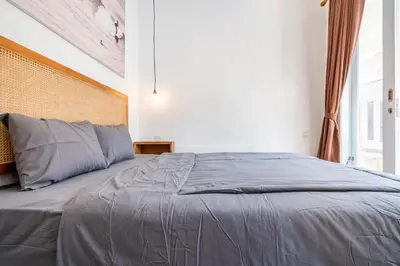 a bedroom with a large bed with gray sheets at Lumturi House - Centrally Located in Kerobokan
