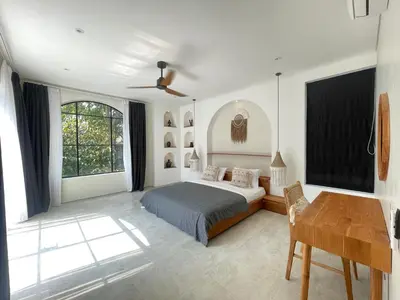 a bedroom with a bed and a desk and windows at Villa Anwa Cove - Gorgeous 6-BR & 2-Pool Villa in Bali in Umalas