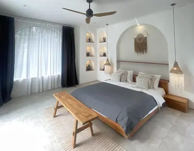 a bedroom with a large bed and a wooden table at Villa Anwa Cove - Gorgeous 6-BR & 2-Pool Villa in Bali in Umalas
