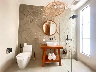 a bathroom with a toilet and a sink and a mirror at Villa Anwa Cove - Gorgeous 6-BR & 2-Pool Villa in Bali in Umalas