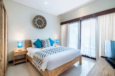 a bedroom with a bed and a large window at Villa Sebelas Legian in Seminyak
