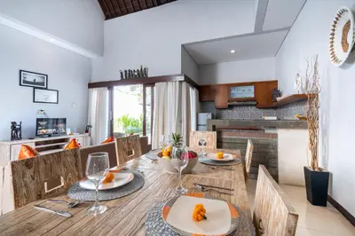 a dining room and kitchen with a wooden table and chairs at Villa Sebelas Legian in Seminyak