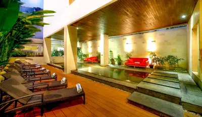 a lobby with chairs and a pool in a building at Euphoria Hotel in Legian