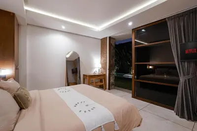 a bedroom with a bed and a view of a tub at Villa Duadewi 4BR in the Heart of Seminyak by Santi Management in Seminyak
