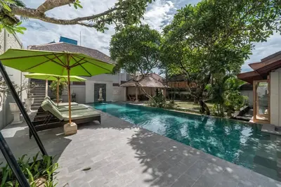 a swimming pool with a green umbrella next to a house at Balinese Luxury Amisha Villa: 4BR in Seminyak in Seminyak