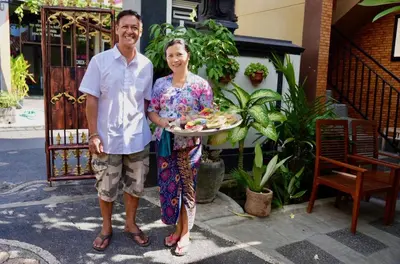 a man and a woman holding a tray of food at Tirtasuci House in Kuta