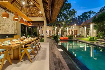 an outdoor dining area with a table and chairs next to a swimming pool at Villa Mahkota Seminyak in Seminyak