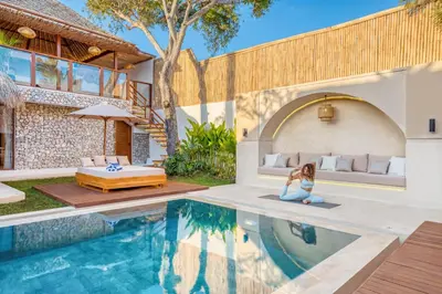 a woman sitting on the edge of a pool next to a house at Villa Miami - New Luxury 7BDR Prime Location in Seminyak