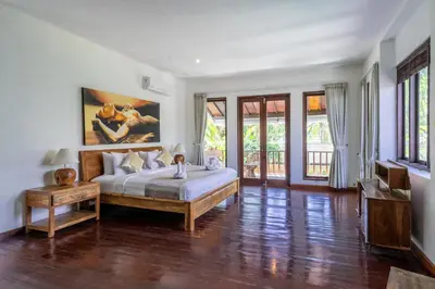 a bedroom with a bed and a table and windows at Enclose living 5Br Villa Center of Seminyak Near Beach in Seminyak