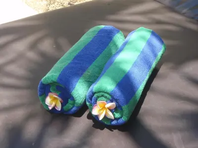 two towels with flowers on them sitting on a bed at The Bali Bliss Villa in Seminyak