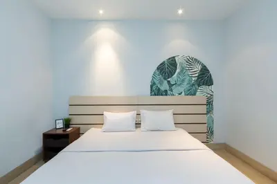 a bedroom with a white bed and a green mural at Cove Matahari Senja in Denpasar