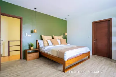 a bedroom with a bed and a green wall at Villa Palm Suites Bali in Seminyak
