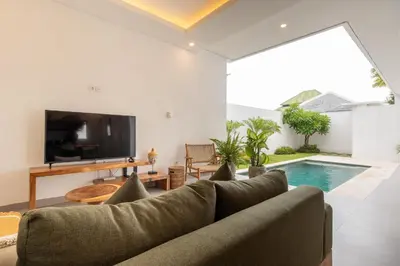 a living room with a couch and a tv and a swimming pool at Casa Moana Seminyak 3BR Stylish Private Pool Villa in Seminyak