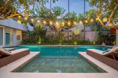 a swimming pool with two lounge chairs and a house at Villa Sunsara 2 - Spacious 4-Bedroom Haven next to Berawa Beach in Canggu