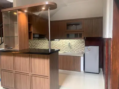 a kitchen with wooden cabinets and a refrigerator at Cahaya Residence The Guest House in Kuta