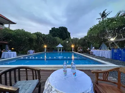 a table with a candle on it next to a swimming pool at New Mekar Jaya Hotel in Legian