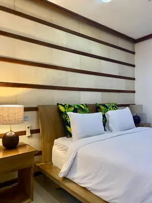 a bedroom with a bed and a table with a lamp at Meilds Property Segara Kuta in Kuta