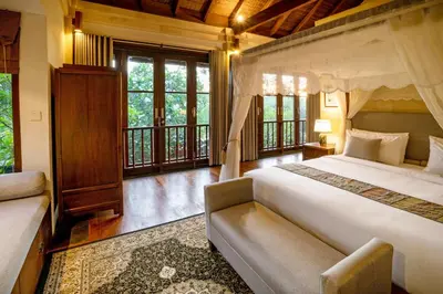 a bedroom with a bed and a couch and windows at Villa Pulung Jimbaran by Nakula in Jimbaran