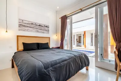 a bedroom with a bed and a sliding glass door at Lumturi House - Centrally Located in Seminyak