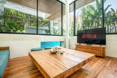 a living room with a wooden table and a tv at Brand new Luxury 5 br villa 200m to Brawah Beach in Canggu