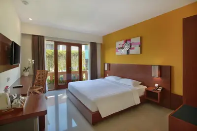 a bedroom with a white bed and a yellow wall at Bali Chaya Hotel Legian in Legian