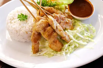 a plate of food with shrimp and rice and sauce at Bali Chaya Hotel Legian in Legian