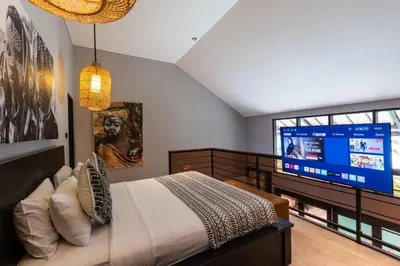 a bedroom with a bed and a large screen tv at Villa Zazu in Seminyak