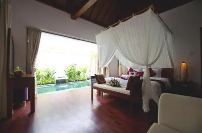 a bedroom with a canopy bed and a pool at Villa Bougainville in Seminyak
