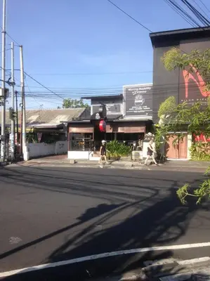 two people crossing a street in front of a building at simple apartment 2 in Seminyak