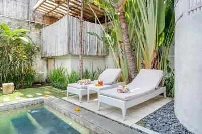 a backyard with two chairs and a swimming pool at Villa Malou in Seminyak