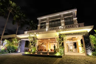 a man stands in front of a house at night at Paragon Hotel Seminyak in Seminyak