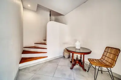 a table and chair in a room with stairs at Villa Arca Seminyak by Santi Management in Seminyak