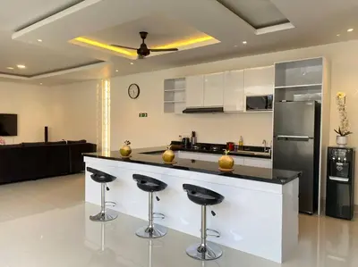 a kitchen with a bar with stools and a refrigerator at Villa Akmali Umalas 2BR with Private Pool & Jacuzzi in Canggu