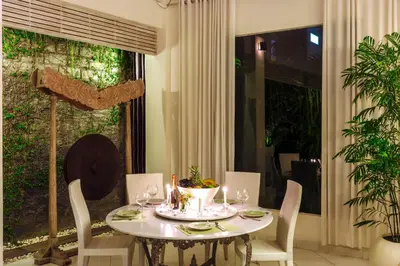 a dining room table with white chairs and a table and a window at Villa Casabola - Seminyak in Seminyak