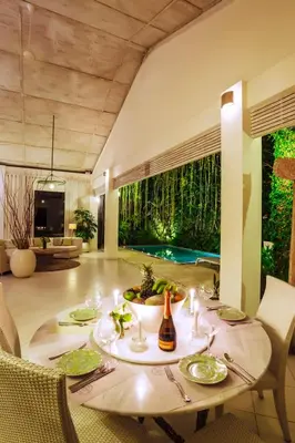 a dining room with a table and chairs and a pool at Villa Casabola - Seminyak in Seminyak