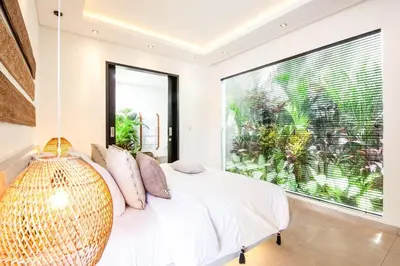 a bedroom with a white bed with a large window at Modern 4 BR Villa 400m to the Beach in Canggu in Canggu