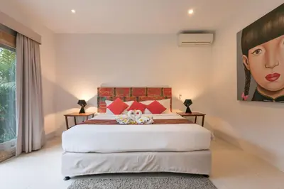 a bedroom with a large bed with a painting on the wall at Villa Briana Seminyak by Villas R Us in Seminyak