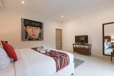 a bedroom with a white bed with a painting on the wall at Villa Briana Seminyak by Villas R Us in Seminyak