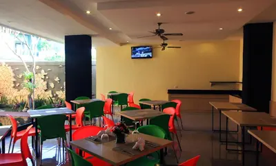 a restaurant with tables and chairs and a tv on the wall at The Agung Residence in Seminyak