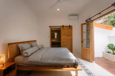 a bedroom with a bed and a sliding glass door at Villa Batu Putih Seminyak in Seminyak
