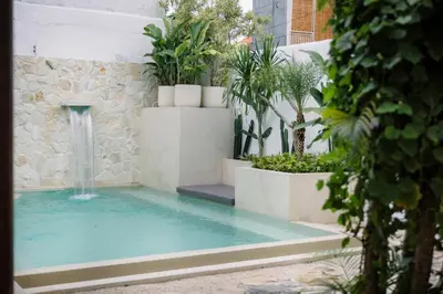 a swimming pool with a waterfall in a garden at Villa Batu Putih Seminyak in Seminyak