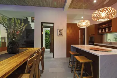 an open kitchen with a large wooden bar with stools at Abivilla in Seminyak