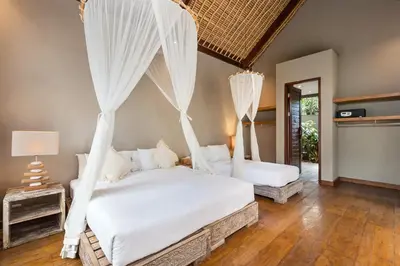 a bedroom with two beds with white mosquito nets at Villa Yoga by Villa Finder in Seminyak