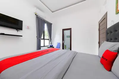 a bedroom with a bed and a tv on a wall at RedDoorz at Lotus House Seminyak in Seminyak
